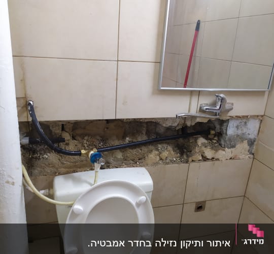 צינור חשוף בקיר חדר אמבטיה עם נזילה